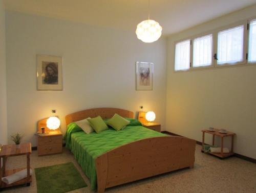 um quarto com uma cama com lençóis verdes e 2 candeeiros em Your relaxing family escape - Beahost em Bibione