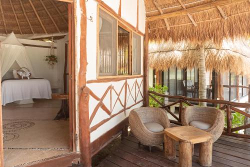 a porch of a resort with chairs and a bed at Casa Takywara in Holbox Island