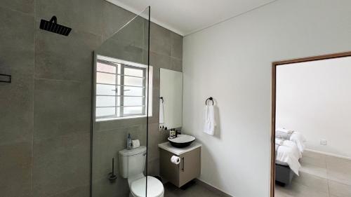 uma casa de banho com um WC e uma cabina de duche em vidro. em Boschkloof Bliss em George