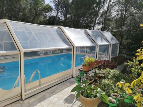 a greenhouse with a swimming pool in a garden at STUDIO meublé indépendant chez l'habitant in Uchaux