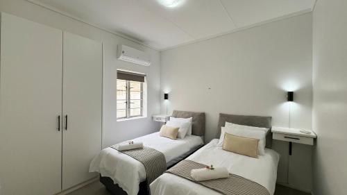 two beds in a small room with white walls at Boschkloof Bliss in George