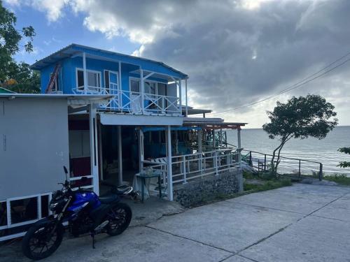 a blue house with a motorcycle parked in front of it at Baba’s Beach Bungalow in Providencia
