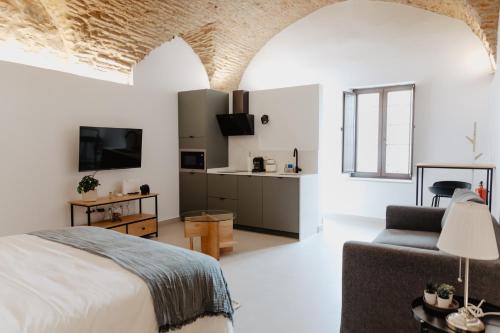 een slaapkamer met een bed, een bank en een tv bij PORTAL DE SANTIAGO in Cáceres