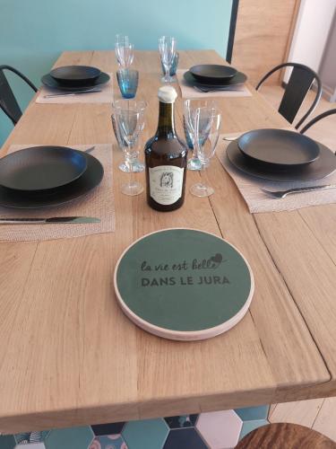 a bottle of wine sitting on a wooden table at Gite les Caravottes 4 Etoiles avec Jacuzzi - JURA in Courlaoux