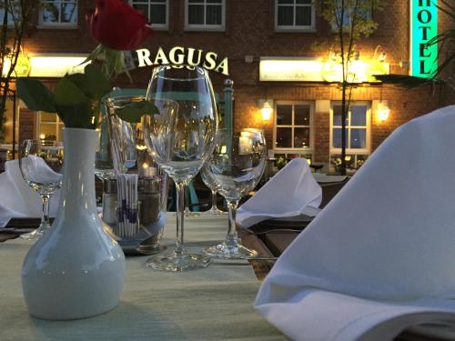 una mesa con copas de vino y un jarrón con una flor en Hotel Ragusa, en Dormagen