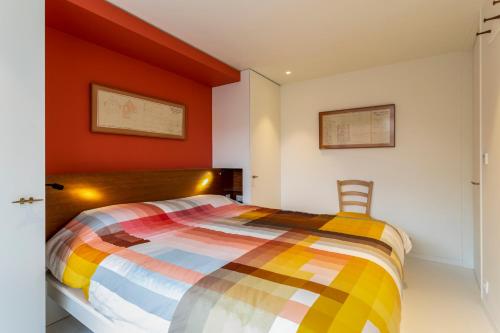 a bedroom with a colorful bed and a chair at Tantor Nostalgie in Nieuwpoort