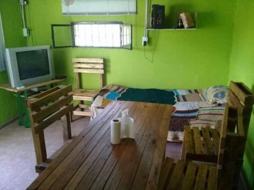 een groene kamer met een houten tafel en een televisie bij Cabañas Mi genio amor in San Luis