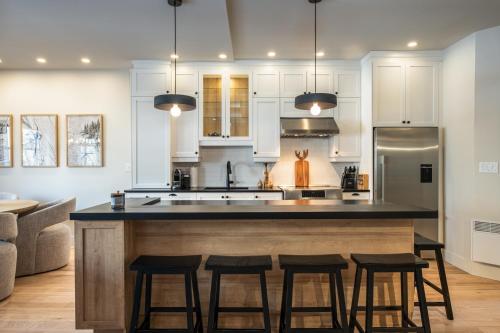 a kitchen with a large island with four bar stools at Tremblant Prestige - Plateau 218-4 in Mont-Tremblant