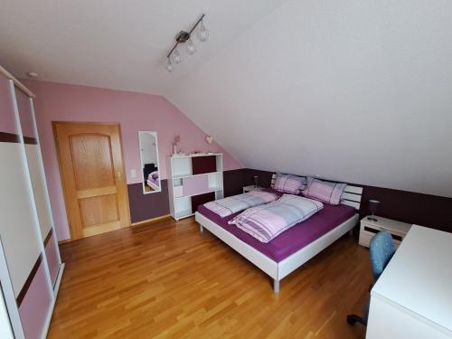 um quarto com uma cama com lençóis roxos e almofadas cor-de-rosa em Ferienwohnung am Schoosberg, Niederkirchen bei Deidesheim em Niederkirchen bei Deidesheim