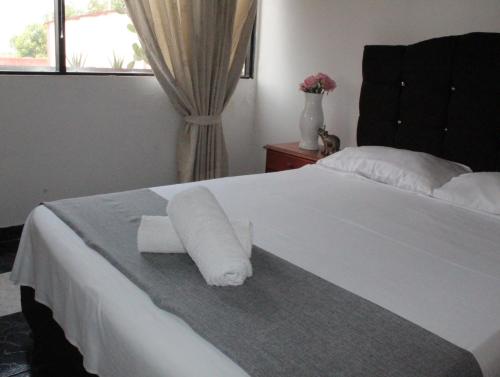 Una cama blanca con un rollo de toallas de papel. en HOTEL DINASTIA REAL NEIVA, en Neiva