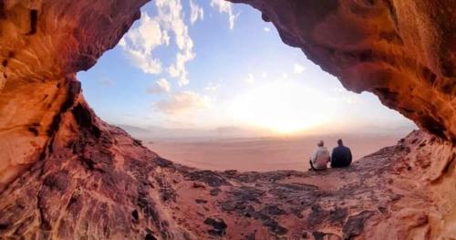 two people sitting in a cave looking at the sunset at Sultan Luxury Camp in Wadi Rum
