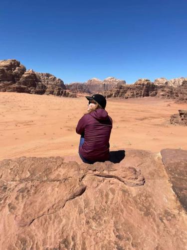 a man sitting on a rock in the desert at Sultan Luxury Camp in Wadi Rum