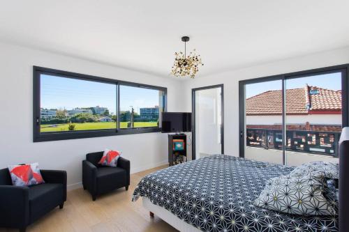 - une chambre avec un lit, 2 chaises et des fenêtres dans l'établissement Villa Contemporaine avec piscine - Face au golf - Plages à pied, à Anglet