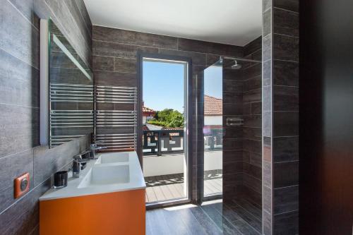 une salle de bain avec un lavabo et une grande fenêtre dans l'établissement Villa Contemporaine avec piscine - Face au golf - Plages à pied, à Anglet