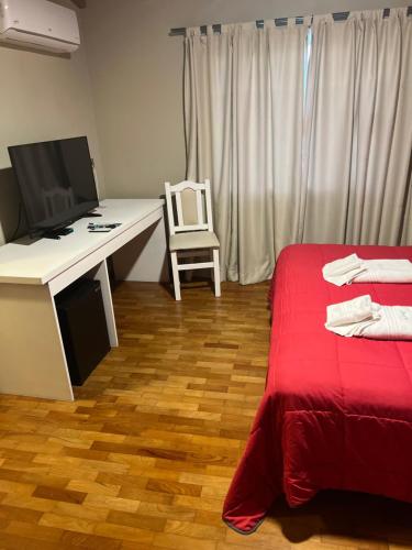 a room with a desk with a computer and a bed at Garden House Hotel in Río Cuarto