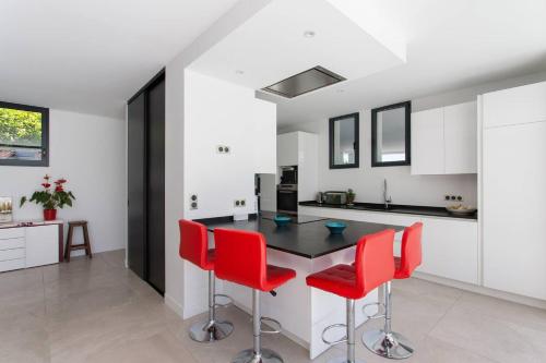 une cuisine avec une table noire et des chaises rouges dans l'établissement Villa Contemporaine avec piscine - Face au golf - Plages à pied, à Anglet