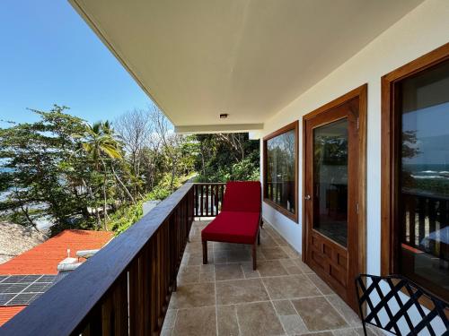 a red chair sitting on the balcony of a house at Ciel y Miel in Colón