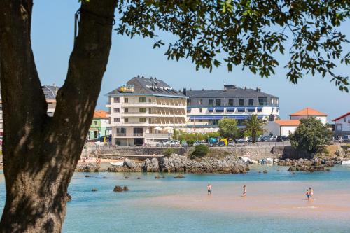 people on a beach with buildings in the water at Apartamentos Astuy in Isla