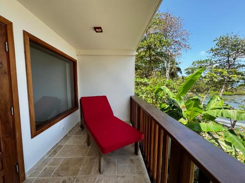 une chaise rouge assise sur un balcon avec fenêtre dans l'établissement Ciel y Miel, à Colón