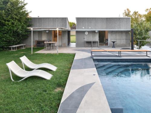 a house with a swimming pool and two white chairs at Sacramora in Faenza
