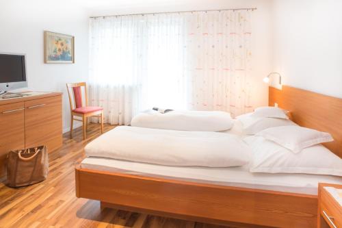 1 dormitorio con 1 cama grande con almohadas blancas en Residence Ferienwohnungen Santner - Moderne zentrale Ferienwohnungen in Naturns Südtirol - mit Parkplatz, en Naturno