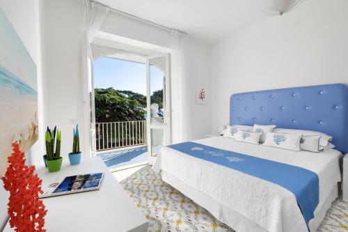 - une chambre blanche avec un lit bleu et un balcon dans l'établissement Villa Kalu' with pool for up to 16 People, à Nerano