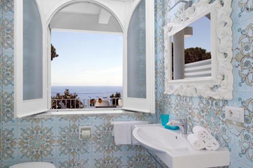 La salle de bains est pourvue d'un lavabo, d'un miroir et d'une fenêtre. dans l'établissement Villa Kalu' with pool for up to 16 People, à Nerano