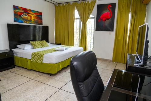 een slaapkamer met een bed, een stoel en een televisie bij Suites & Apartments San Benito - Zona Rosa in San Salvador