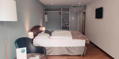 a bedroom with a bed and a table and a chair at Hôtel Rallye & Entrées aux Bains de la Gruyère in Bulle
