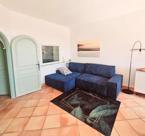 een woonkamer met een blauwe bank en een deur bij TRES BEL APPARTEMENT VUE MER - Piscine - Tennis et Golf in Saint-Cyr-sur-Mer