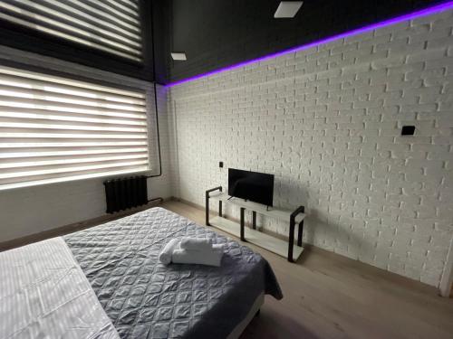 a bedroom with a bed and a tv on a wall at 1-комнатная квартира Виноградова 12 in Ustʼ-Kamenogorsk