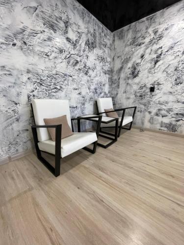 2 Stühle und ein Tisch in einem Zimmer mit einer Wand in der Unterkunft 1-комнатная квартира Виноградова 12 in Öskemen
