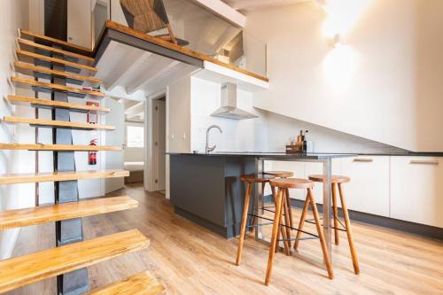 a kitchen with a counter and some wooden stools at Apartamento Porta14 4 in Chaves