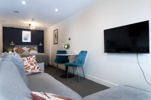a living room with a couch and a tv and a table at Midsummer Apartments "Free On-Site Parking & Sky TV" in Peterborough