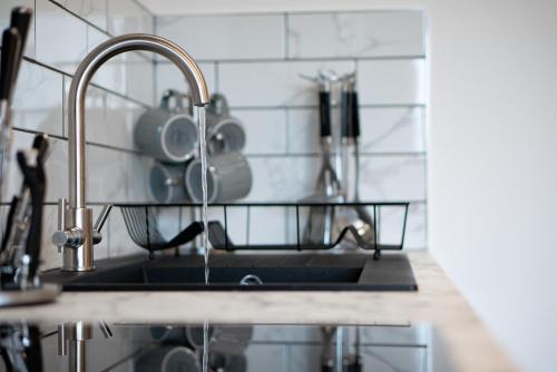 um lavatório de cozinha com uma torneira com copos em Midsummer Apartments "Free On-Site Parking & Sky TV" em Peterborough