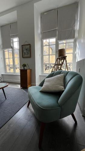 a living room with a blue couch and two windows at Appartement de charme in Bayeux