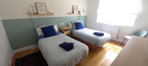 Habitación con 2 camas y almohadas azules. en Apartamento Miramar, en Hondarribia