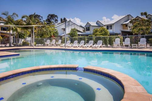 a large swimming pool with lounge chairs in a resort at Serene Escape with Resort Amenities in Noosaville