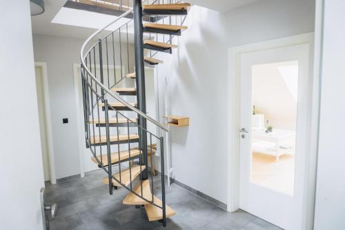 a metal spiral staircase in a white room with a mirror at Design Apartment in Hallbergmoos in Hallbergmoos