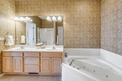 Un baño con bañera, lavabo y espejo. en Lakeside Osage Beach Condo in Lands End Community, en Osage Beach