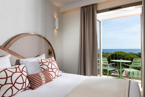 a bedroom with a bed and a view of the ocean at H&ocirc;tel du Parc Cavalaire sur Mer in Cavalaire-sur-Mer