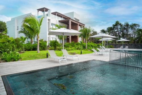une villa avec une piscine et une maison dans l'établissement Ocean Point Beachfront Residences - Apartment A1, à Pointe-aux-Piments