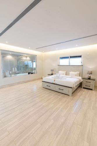 a white bedroom with a large bed and a hardwood floor at Tiffany Beach in Durat Alarous