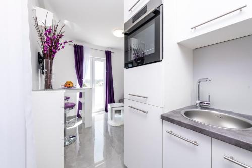 a white bathroom with a sink and a mirror at Apartments Lana in Mlini