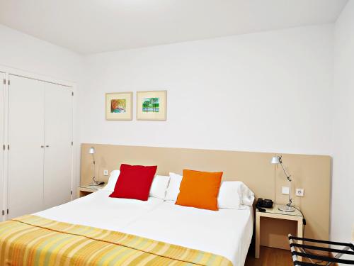 a bedroom with a white bed with colorful pillows at Hotel Patagonia Sur in Cádiz