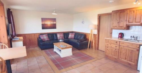 a living room with a couch and a table at Dolphin View Cottages 2 in Portmahomack