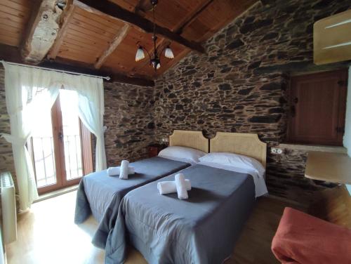 een slaapkamer met 2 bedden en een stenen muur bij VILA PEREGRINA-taxi gratis in Arzúa