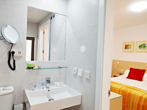 a white bathroom with a sink and a bed at Hotel Patagonia Sur in Cádiz