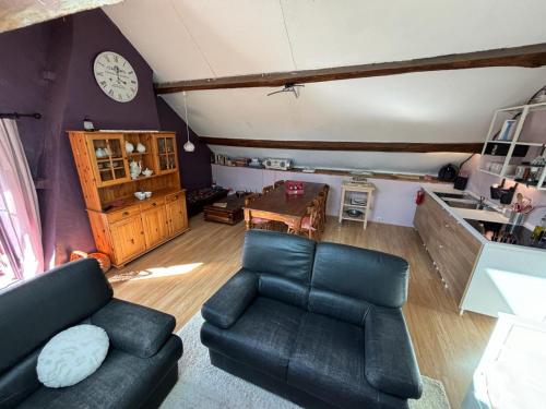 a living room with a couch and a clock on the wall at La Maison du bonheur - Gîte RULINA - Corancy in Corancy
