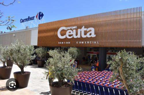 a shopping center with trees in front of a store at Apartamentos Murallas Merinies in Ceuta